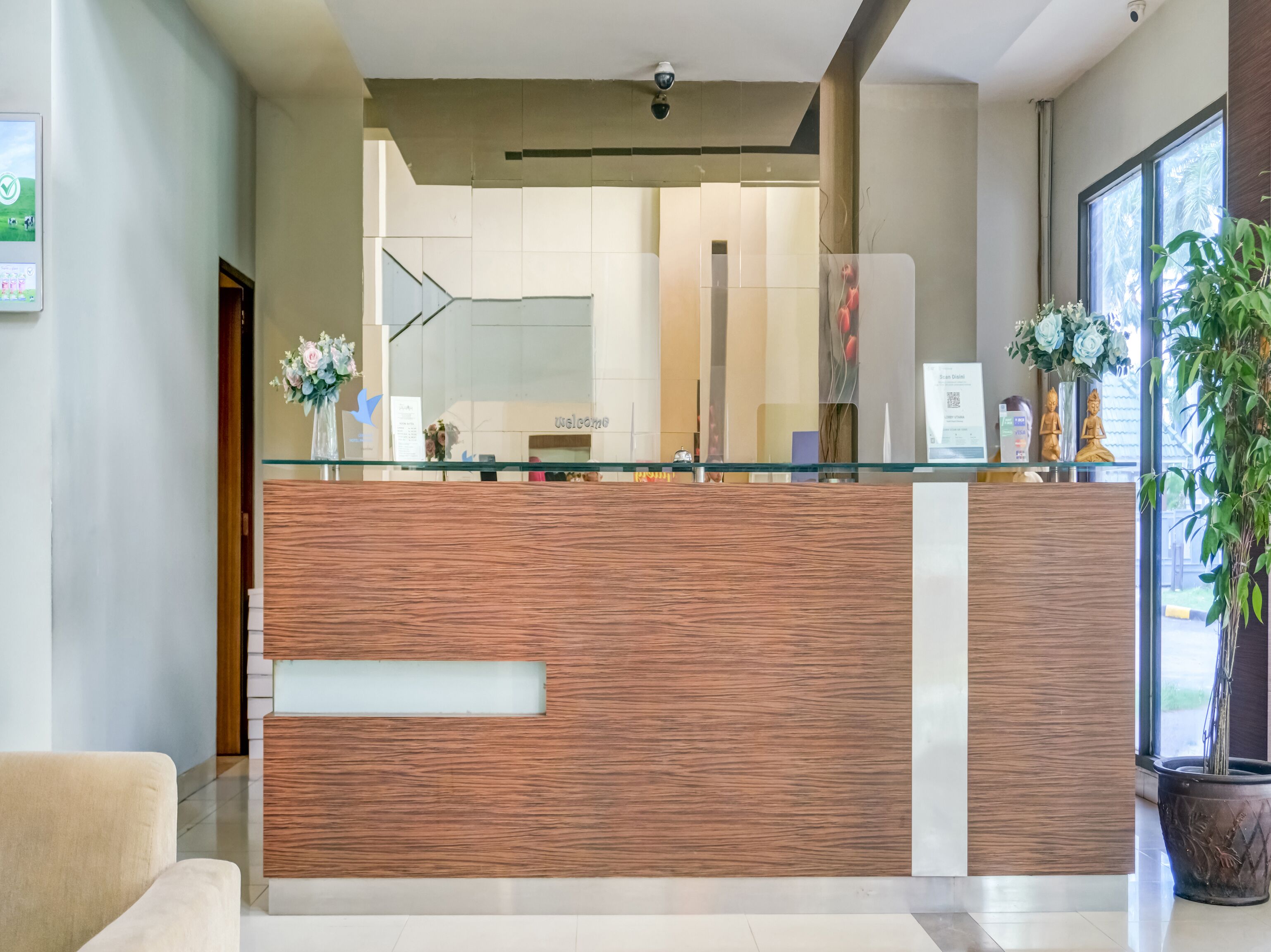 A reception desk with a wooden panel design, a glass partition, and a 'Welcome' sign in the background.