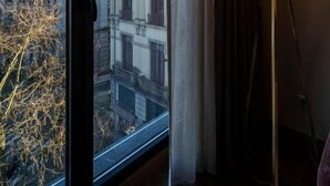 A room with a large window offering a view of a historic building with a clock tower. - TURIM Oporto Hotel (Porto)
