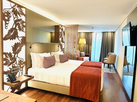 Camera d'albergo con un letto, comodino con telefono, una scrivania, una sedia, una televisione e vista esterna.