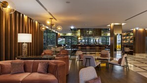 A modern lounge area with sofas, chairs, a bar, and a view of the cityscape. - TURIM Oporto Hotel (Porto)