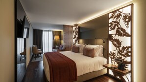 A hotel room with a bed, bedside table, lamp, and a decorative partition. - TURIM Oporto Hotel (Porto)