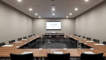 Uma sala de conferências com uma mesa comprida, cadeiras e uma tela de projetor exibindo "TURIM HOTELS".