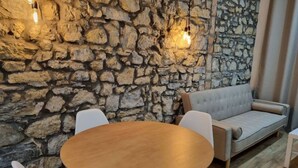 A stone wall, a round wooden table, and a sofa in a room.