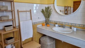 A bathroom with a white sink, a mirror, a towel rack, and shelves with baskets.