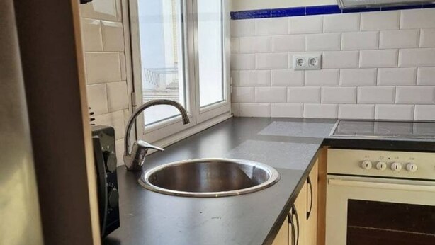 A kitchen with a stainless steel sink, a window, and a stove.