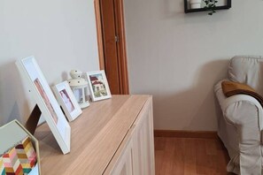 Een kamer met een houten bureau, een beige bank en een deur.