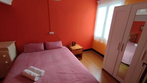 Ein Zimmer mit einem Bett, einem Nachttisch, einem Kleiderschrank und einem fenster mit Vorhängen.