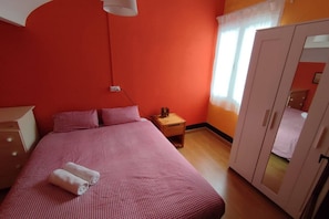 Een kamer met een bed, nachtkastje, kast en raam met gordijnen.