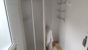 Ein Badezimmer mit Dusche, Handtuchhalter und Toilette.