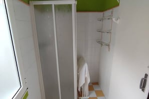 Een badkamer met een douche, een handdoekrek en een toilet.