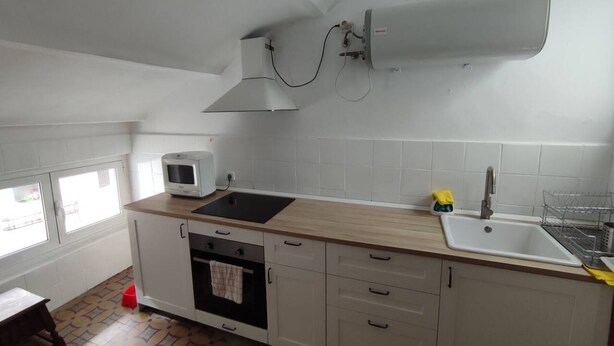 Eine Küche mit Mikrowelle, Backofen, Spüle und einem Fenster.