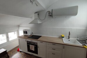A kitchen with a microwave, oven, sink, and a window.