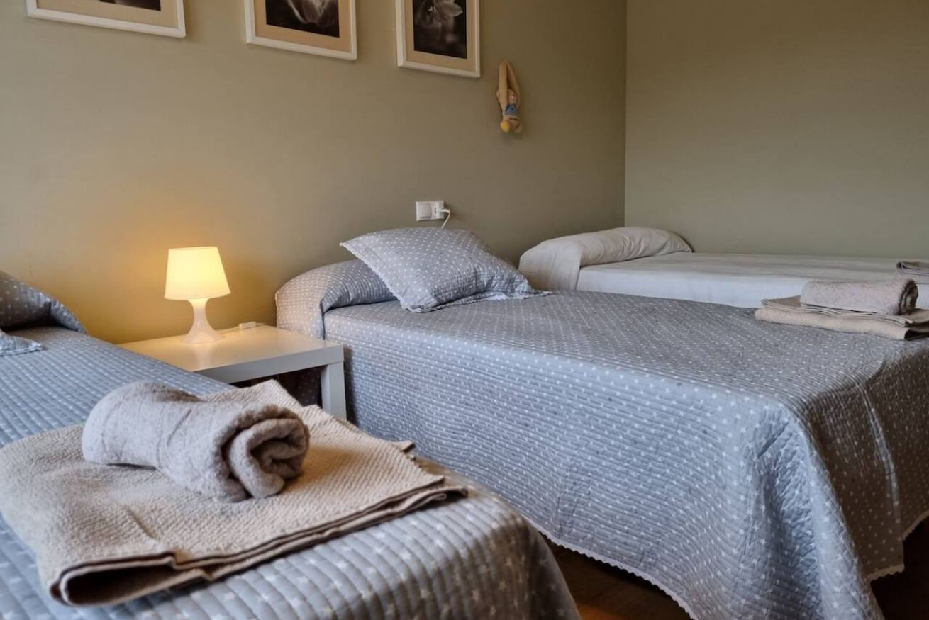 Habitación de hotel con dos camas, una mesita de noche con lámpara y un reloj en la pared.