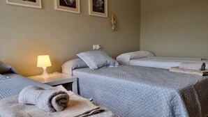 A hotel room with two beds, a nightstand with a lamp, and a wall-mounted clock.