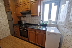 A kitchen with wooden cabinets, a stainless steel sink, a microwave, and a white refrigerator.