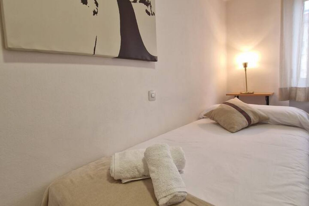 A hotel room with a bed, a nightstand, a lamp, and a wall art piece.