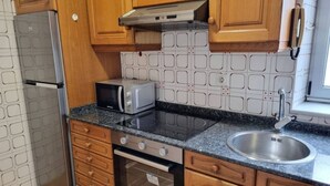Eine Küche mit Holzausstattung, einer Edelstahlspüle, einer Mikrowelle, einem Herd und einem Kühlschrank.