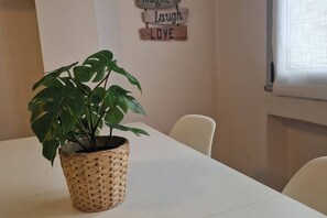 Una habitación con una mesa blanca, una planta en maceta y una pared decorada con letreros motivacionales.