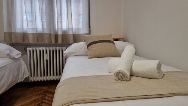 Ein Hotelzimmer mit Bett, Heizkörper und einem mit Vorhängen versehenen Fenster.