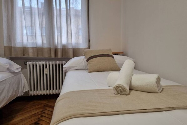 Una habitación de hotel con cama, radiador y ventana con cortinas.