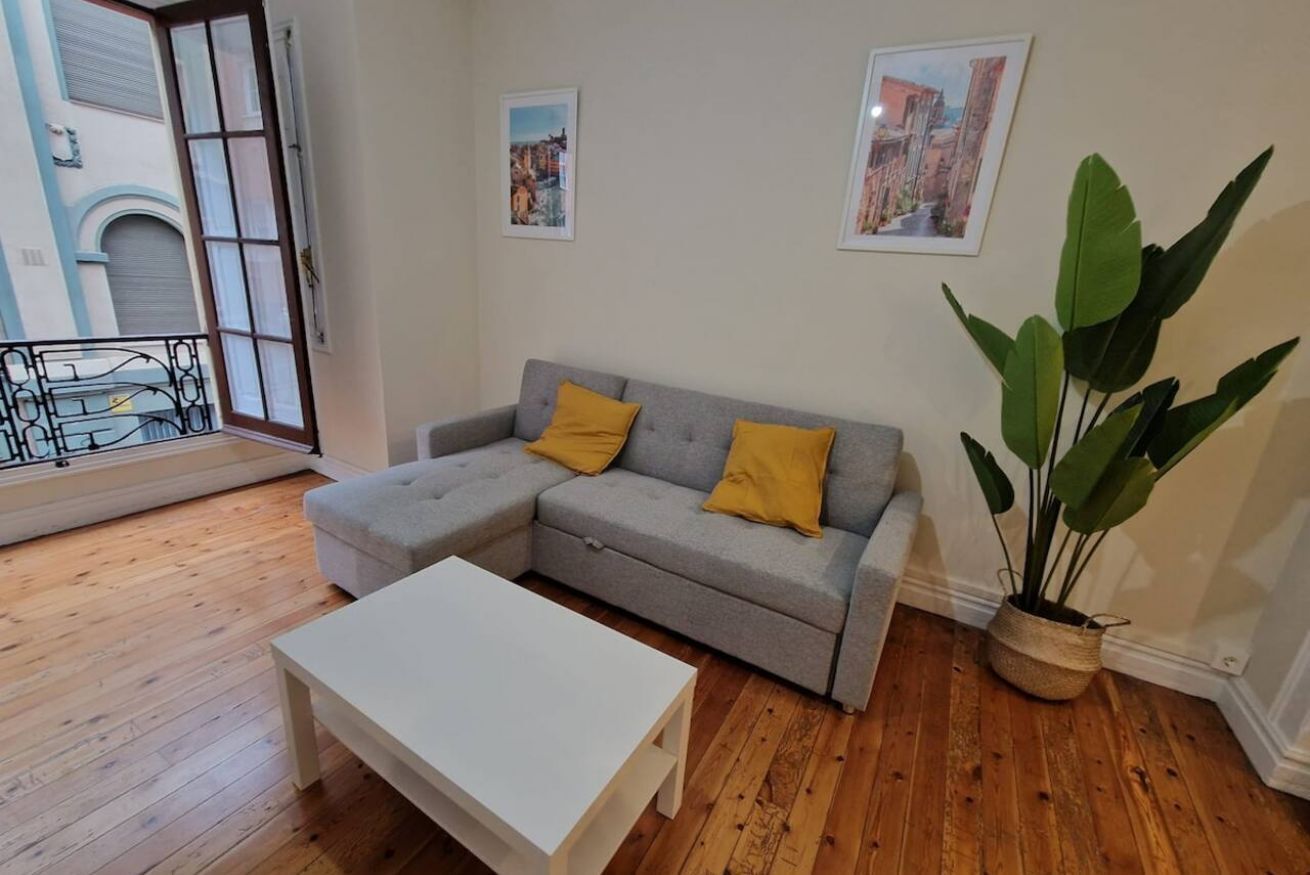 Un salon avec un canapé gris, une table basse blanche et une grande plante en pot.