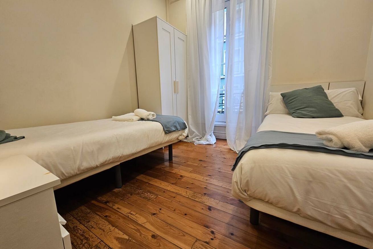 Une chambre avec deux lits simples, une armoire et un plancher en bois.