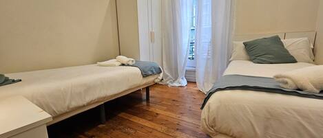 A bedroom with two single beds, a wardrobe, and a wooden floor.