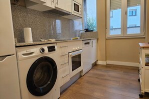 A compact kitchen with a washing machine, a microwave, and a small oven.