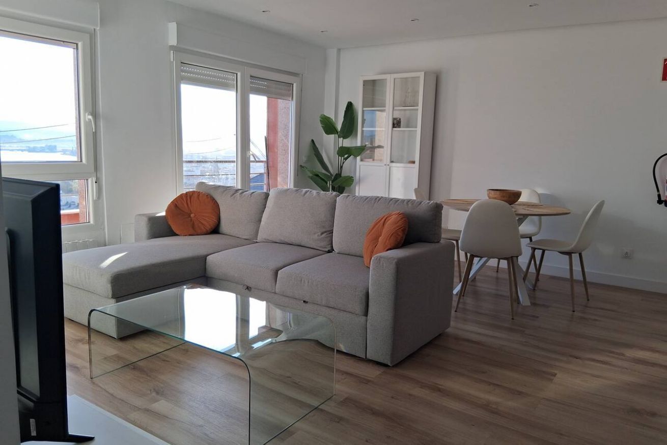A modern living room with a sectional sofa, a glass coffee table, and a dining area with chairs and a table.
