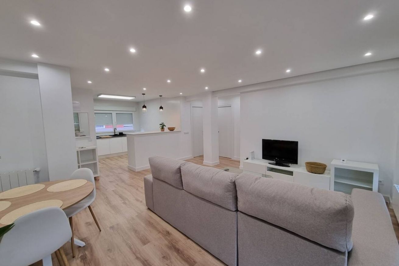 Una sala de estar moderna con un sofá, una mesa de comedor y un televisor.