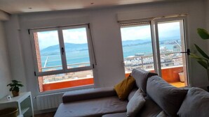 A modern living room with a sofa, large windows, and a view of the sea. - C01A01 Apartamento Moderno con vistas al mar (Santander)