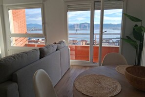 Un salon avec un canapé, une table à manger et des chaises, une vue sur un pont et une plante.