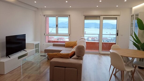 Una sala de estar moderna con televisor de pantalla plana, una mesa de centro de vidrio, un sofá y un comedor con mesa y sillas.
