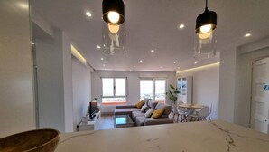 A modern living room with a sofa, coffee table, and dining table. - C01A01 Apartamento Moderno con vistas al mar (Santander)