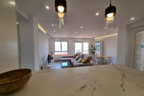A modern living room with a sofa, coffee table, and dining table. - C01A01 Apartamento Moderno con vistas al mar (Santander)