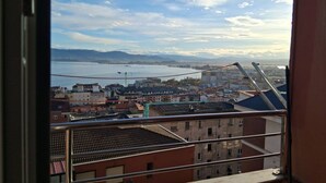 A cityscape with buildings, a body of water, and mountains in the distance. - C01A01 Apartamento Moderno con vistas al mar (Santander)