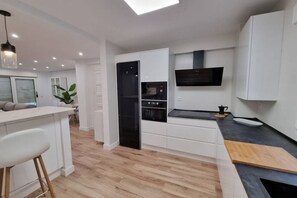 A modern kitchen with white cabinetry, a black oven, and a built-in microwave. - C01A01 Apartamento Moderno con vistas al mar (Santander)