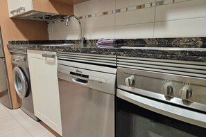 Une cuisine compacte équipée d’un lave-linge, d’un lave-vaisselle et d’une cuisinière.
