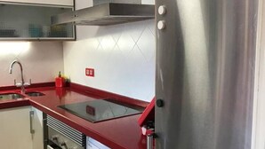 A kitchen with stainless steel appliances, a red countertop, and a tiled backsplash. - 130A Beautiful Apartment in Cimadevilla by R2R (Gijón)