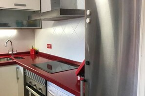 A kitchen with stainless steel appliances, a red countertop, and a tiled backsplash. - 130A Beautiful Apartment in Cimadevilla by R2R (Gijón)