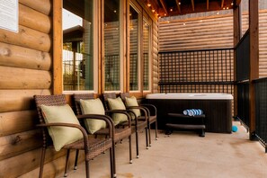 A log cabin with wicker chairs and a hot tub.