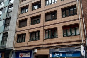 A multi-story building with a tiled facade, multiple windows, and storefronts including signs for 'PEREDA' and 'Roca.'