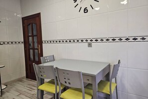 Un comedor con una mesa y sillas, un reloj en la pared y una puerta.