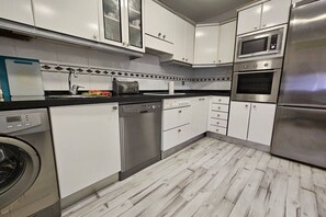 A modern kitchen with stainless steel appliances, white cabinetry, and a patterned backsplash.