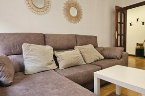 Ein Wohnzimmer mit braunem Sofa, einem weißen Couchtisch und dekorativen Wandspiegeln.