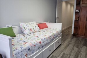 A bed with floral bedding, a green pillow, and a red pillow. - 153a - 3-Bedroom Apartment in the La Arena Neighborhood by R2R (Gijón)