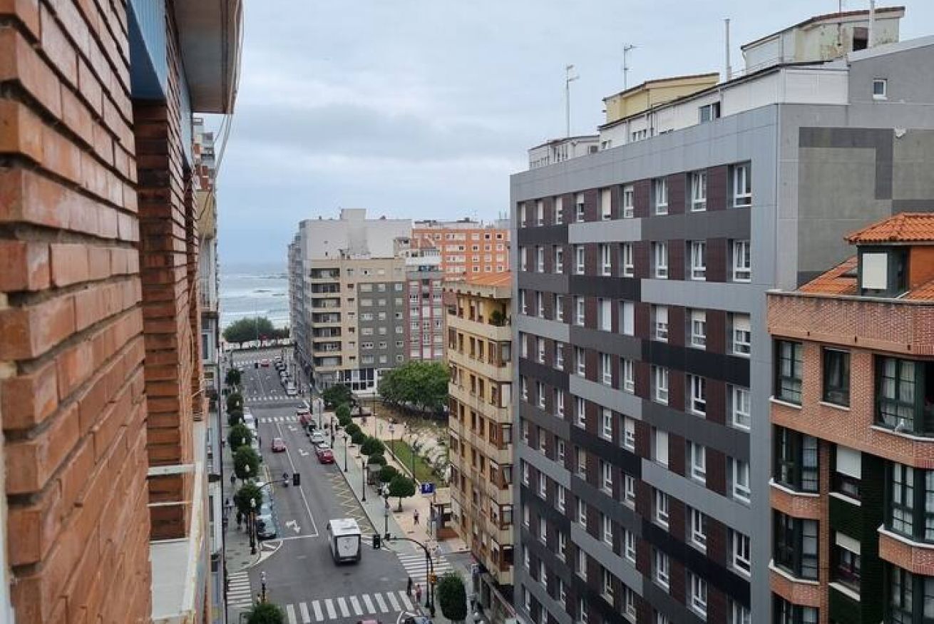 A multi-story urban building with a street view, including a road with vehicles and a pedestrian crossing.