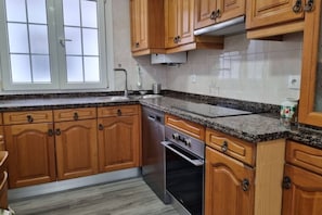 Una cocina con armarios de madera, horno de acero inoxidable y encimera de granito.