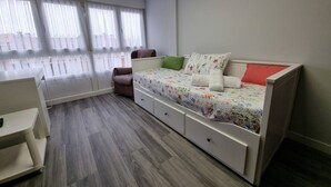 Une chambre à coucher avec un lit, une chaise, un bureau et une fenêtre avec des rideaux.