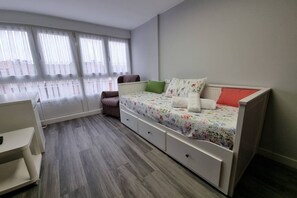 A bedroom with a bed, a chair, a desk, and a window with curtains. - 153a - 3-Bedroom Apartment in the La Arena Neighborhood by R2R (Gijón)